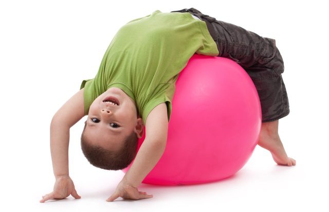 A little boy building on his core strength with a ball