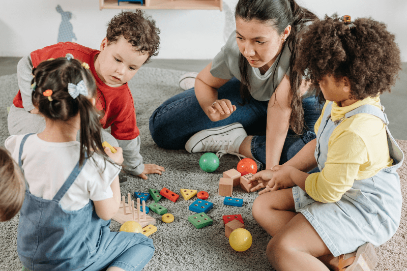 Two children playing together at preschool, sharing toys and smiling.