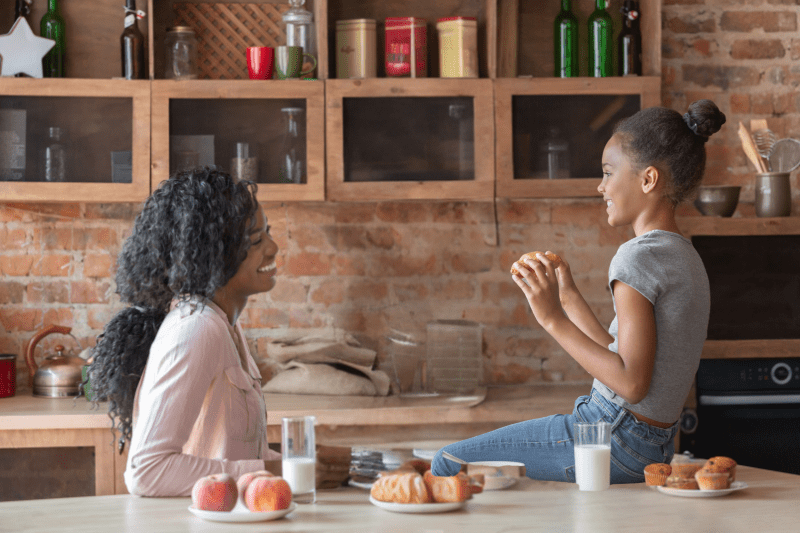 Parent having a serious but friendly conversation with their child at the kitchen table.