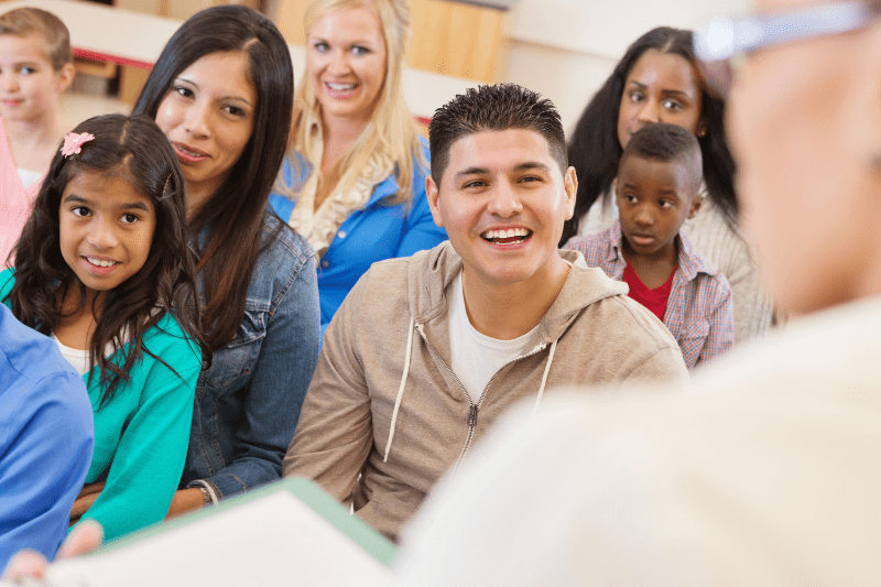 Parents and children at a school orientation day, exploring classrooms and meeting teachers.
