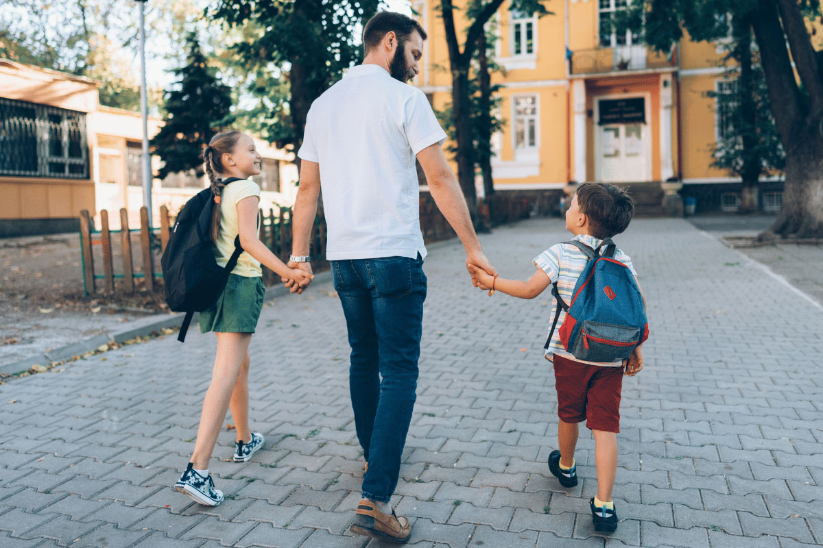 A single parent walking their children to school, emphasising why child psychologists in Sydney's Northern Beaches recommend sharing family background details with teachers