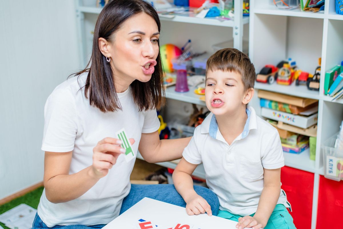 Speech pathologist supporting a young child with articulation practice during a Medicare-eligible speech therapy session at Kids First in Brookvale.