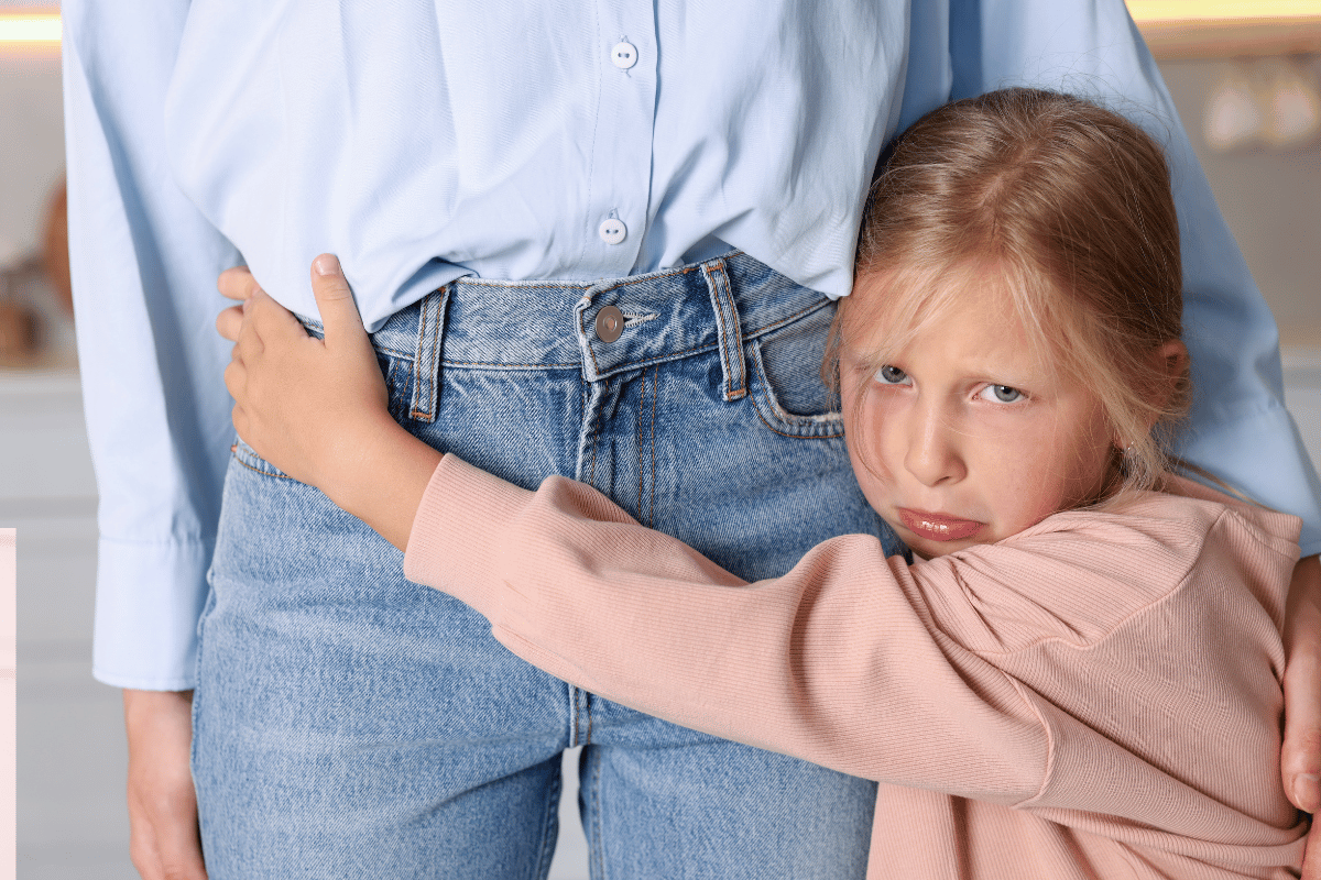 Young girl holding tightly onto an adult for comfort and reassurance, representing separation anxiety and anxious child behaviour.